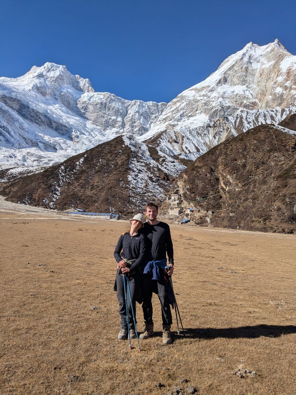 Trekkers pose before a Himalayan village and vast snow-capped peaks