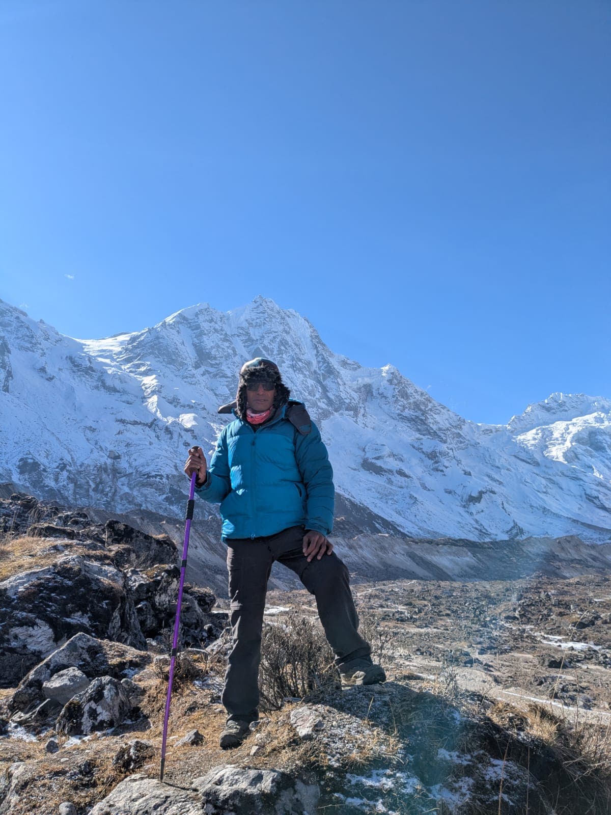 Man on rocky trail with snow-capped Himalayan mountains