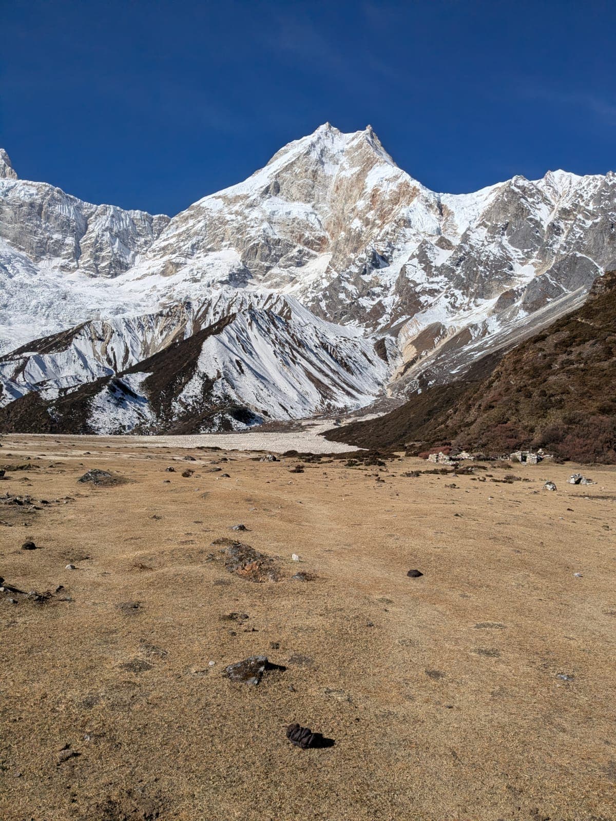 Manaslu mountain towers over a vast, dry Himalayan valley and village