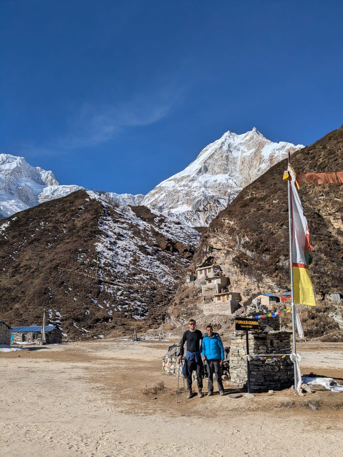 Trekkers at Pungen Gumba village with snow-capped Manaslu mountains