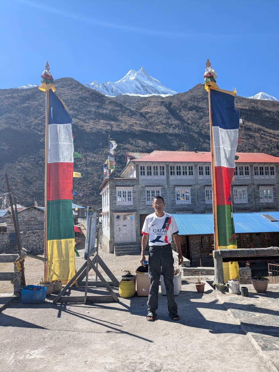 Trekker in a Himalayan village with Manaslu mountain and prayer flags