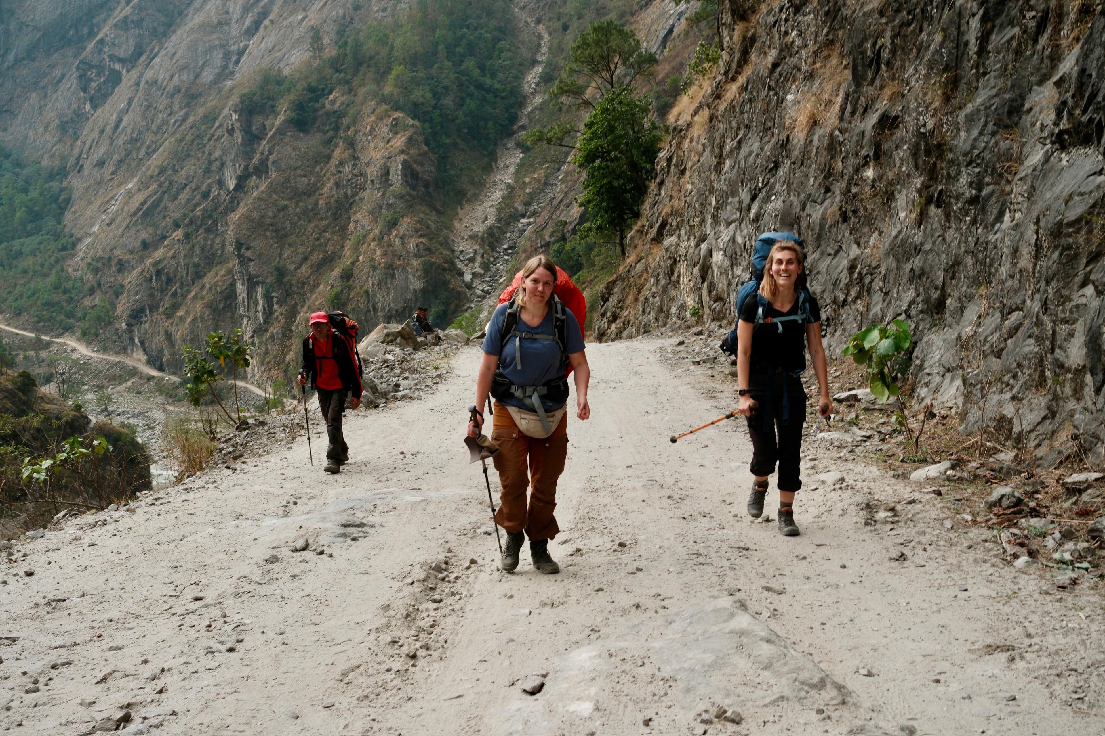 Trekkers walking a dusty trail through a rugged Himalayan valley