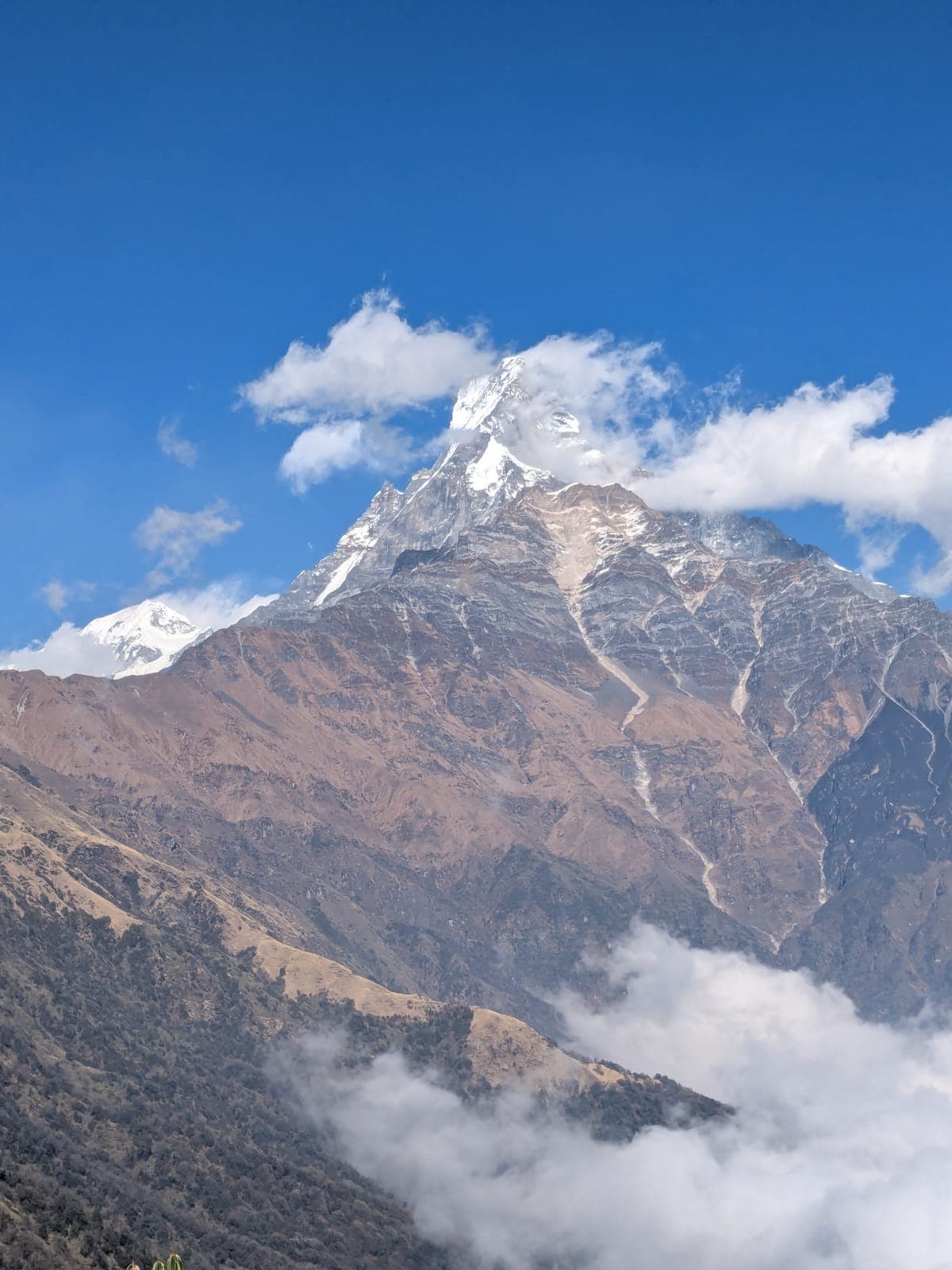 Snow-capped Machapuchare peak in the Annapurna Himalayas surrounded by clouds