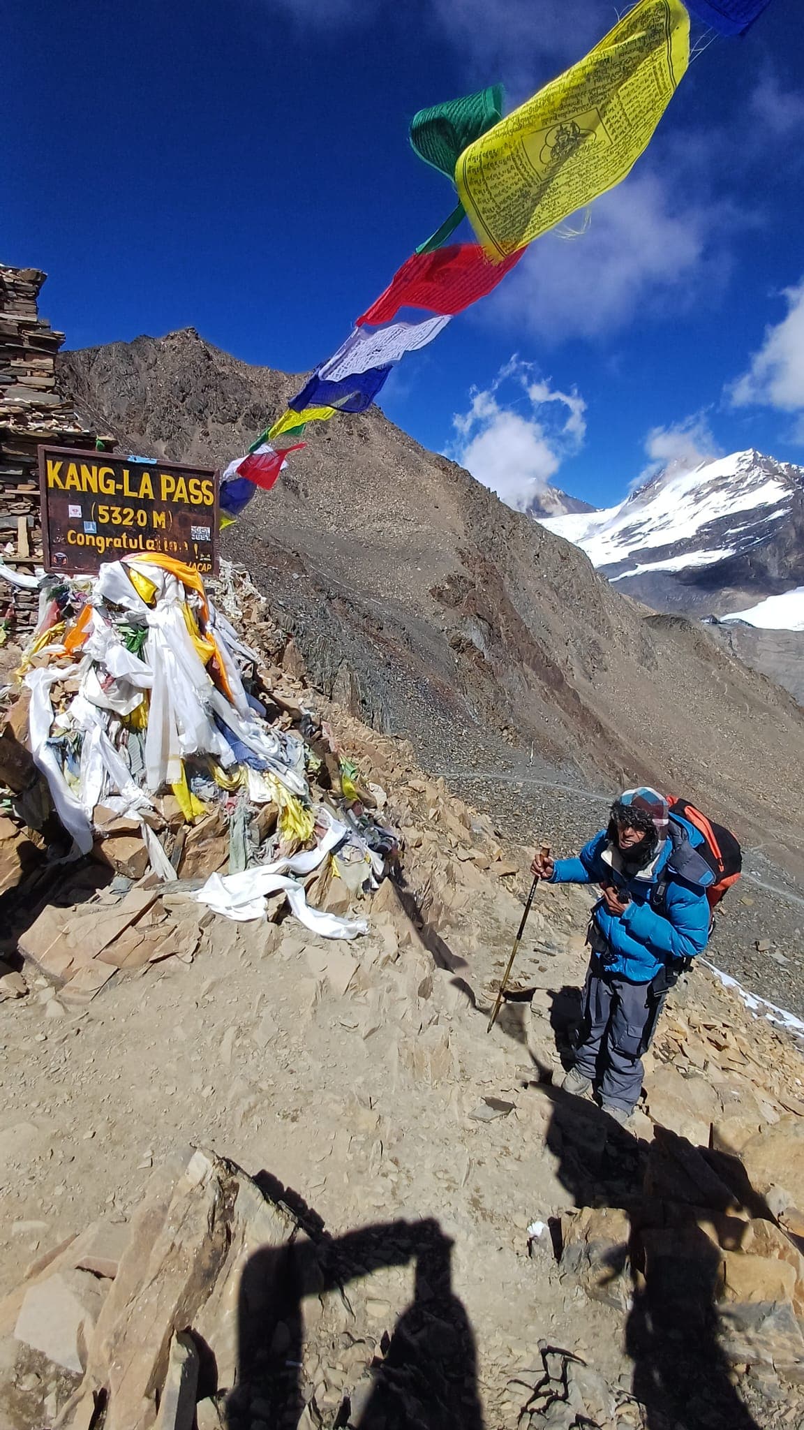 Trekker at Kang-La Pass (5320m) among prayer flags and snow-capped mountains