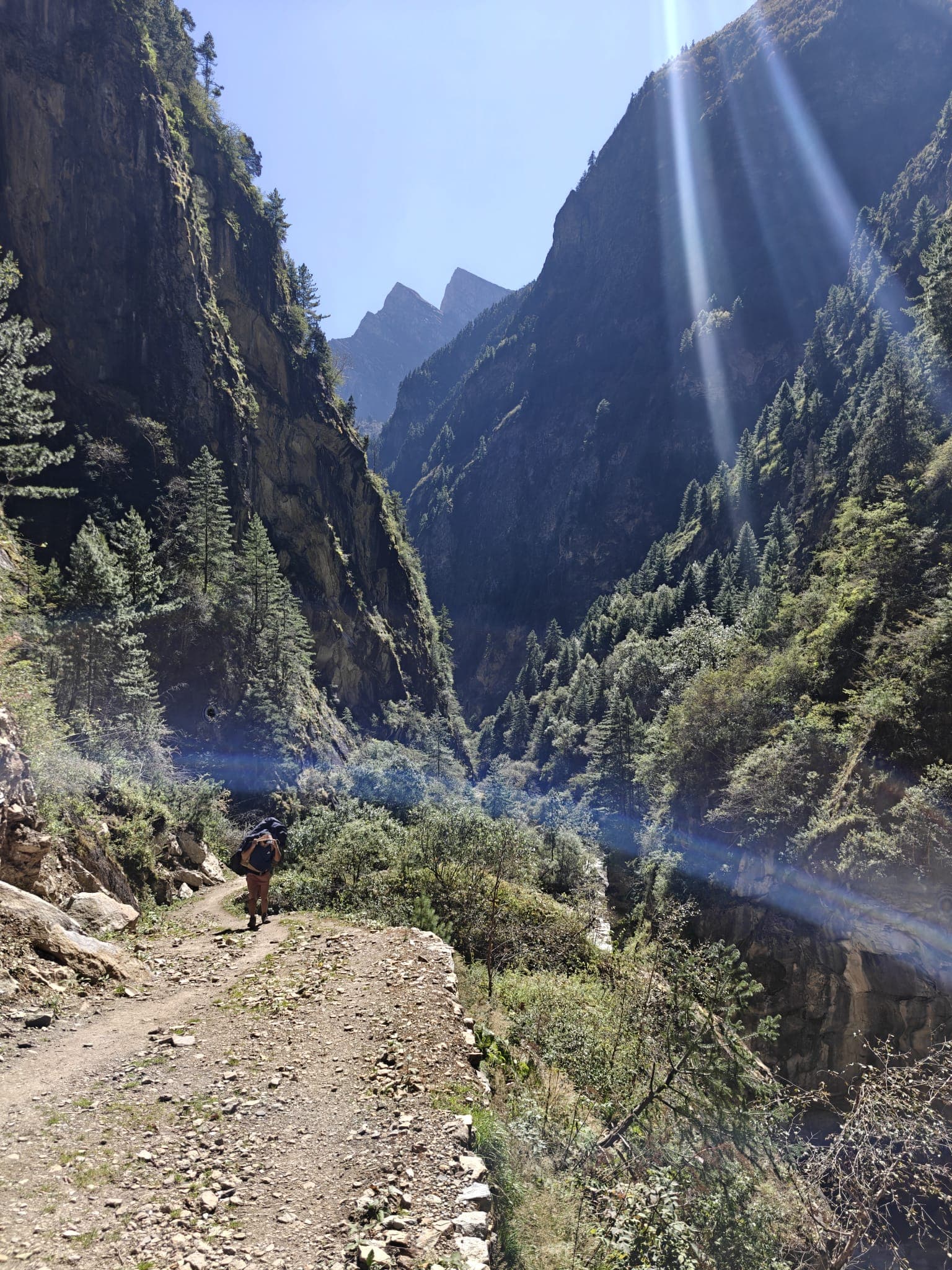 Trekker on a rocky trail in a deep, sunlit mountain gorge