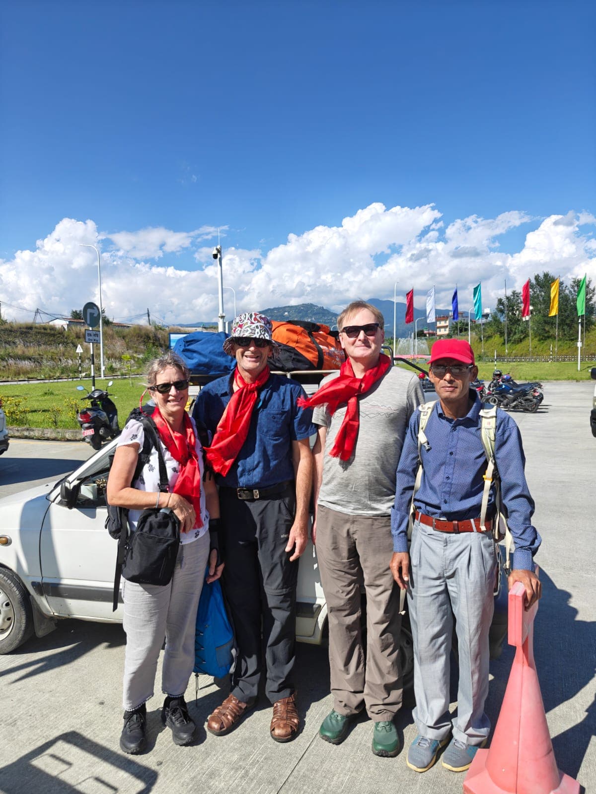 Trekkers and guide in Nepal with colorful flags and Himalayan foothills
