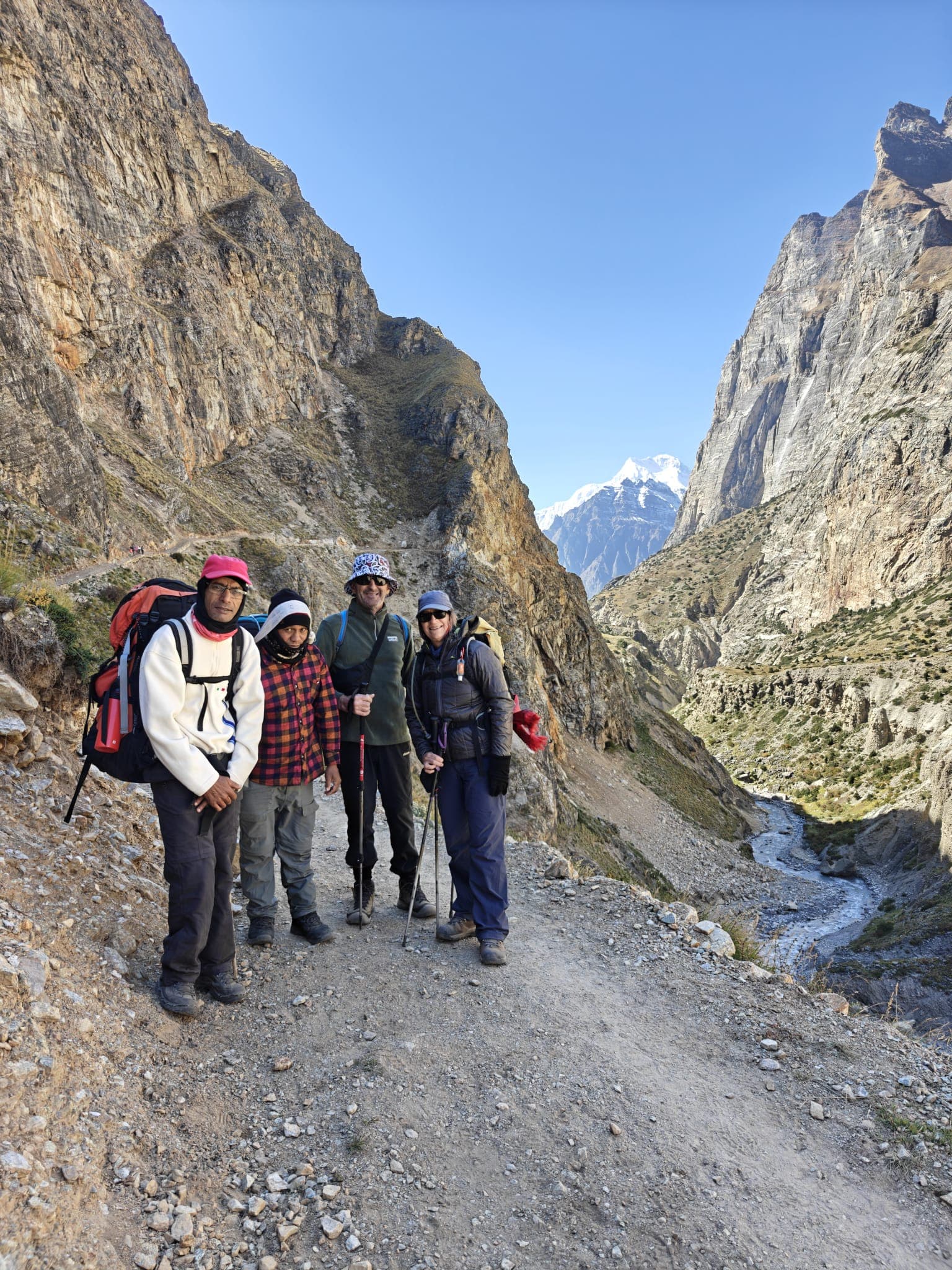 Four trekkers on a rugged trail through a Himalayan gorge