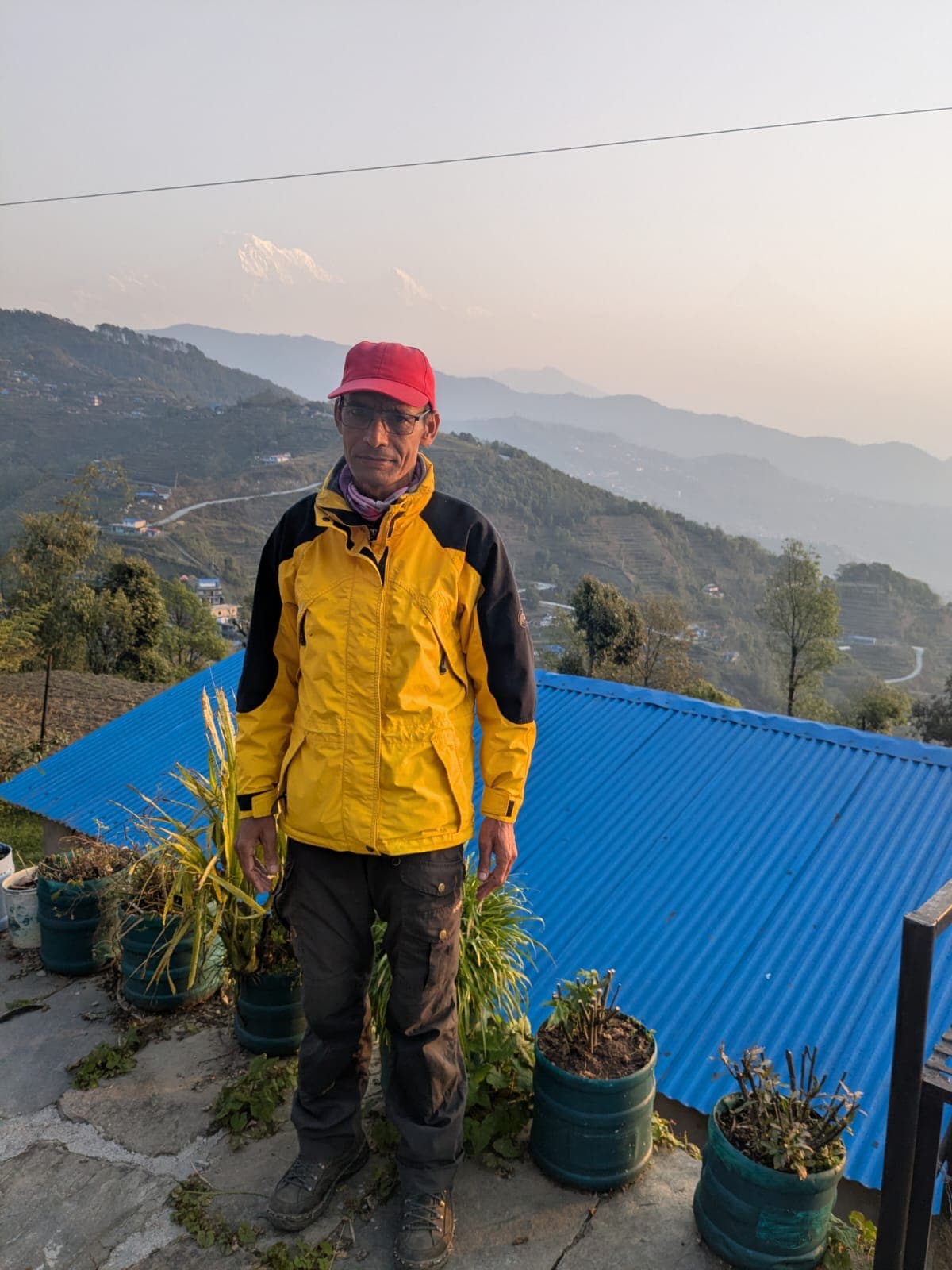 Trekker in yellow jacket overlooks Himalayan peaks and terraced villages