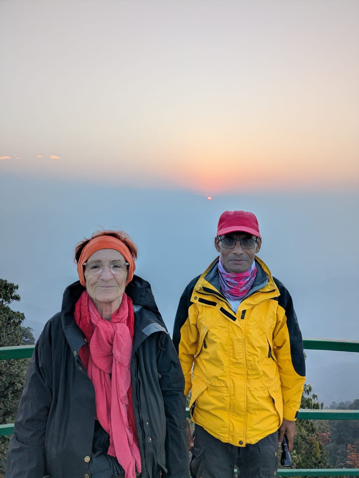 Trekkers on a mountain viewpoint during a hazy sunset